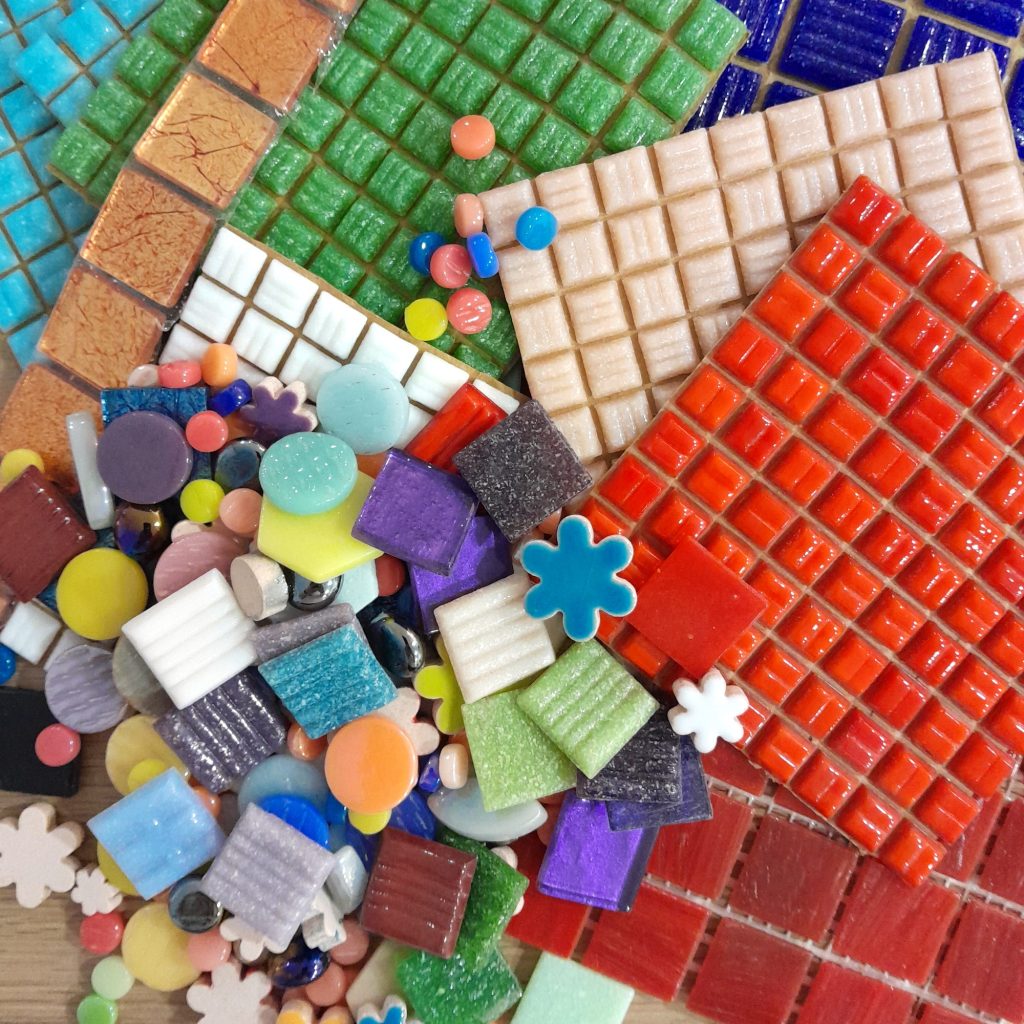 square mosaic tiles, shaped ceramic mosaic embellishments and metallic mosaic tiles together on a table