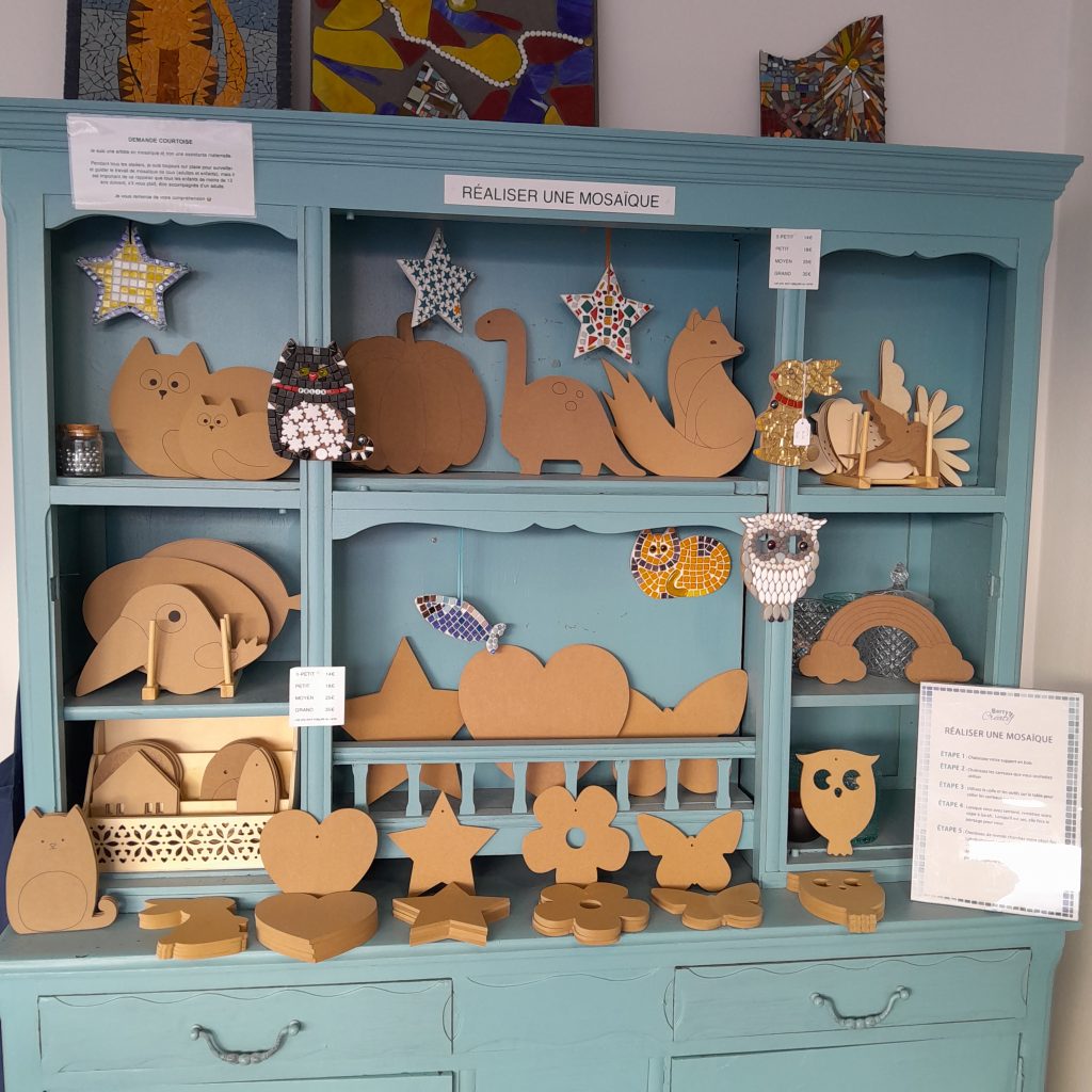 turquoise display cabinet with a big selection of wooden mdf shapes ready to mosaic onto during mosaic workshops in Secondigny France